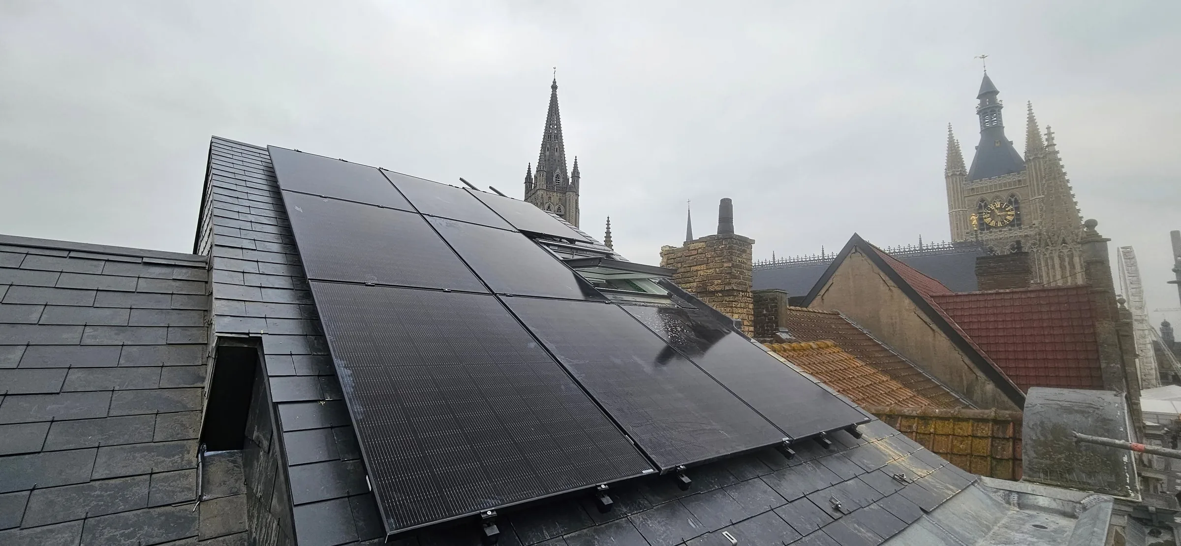 Zonnepanelen op een dak in Ieper, met zicht op de Lakenhalle